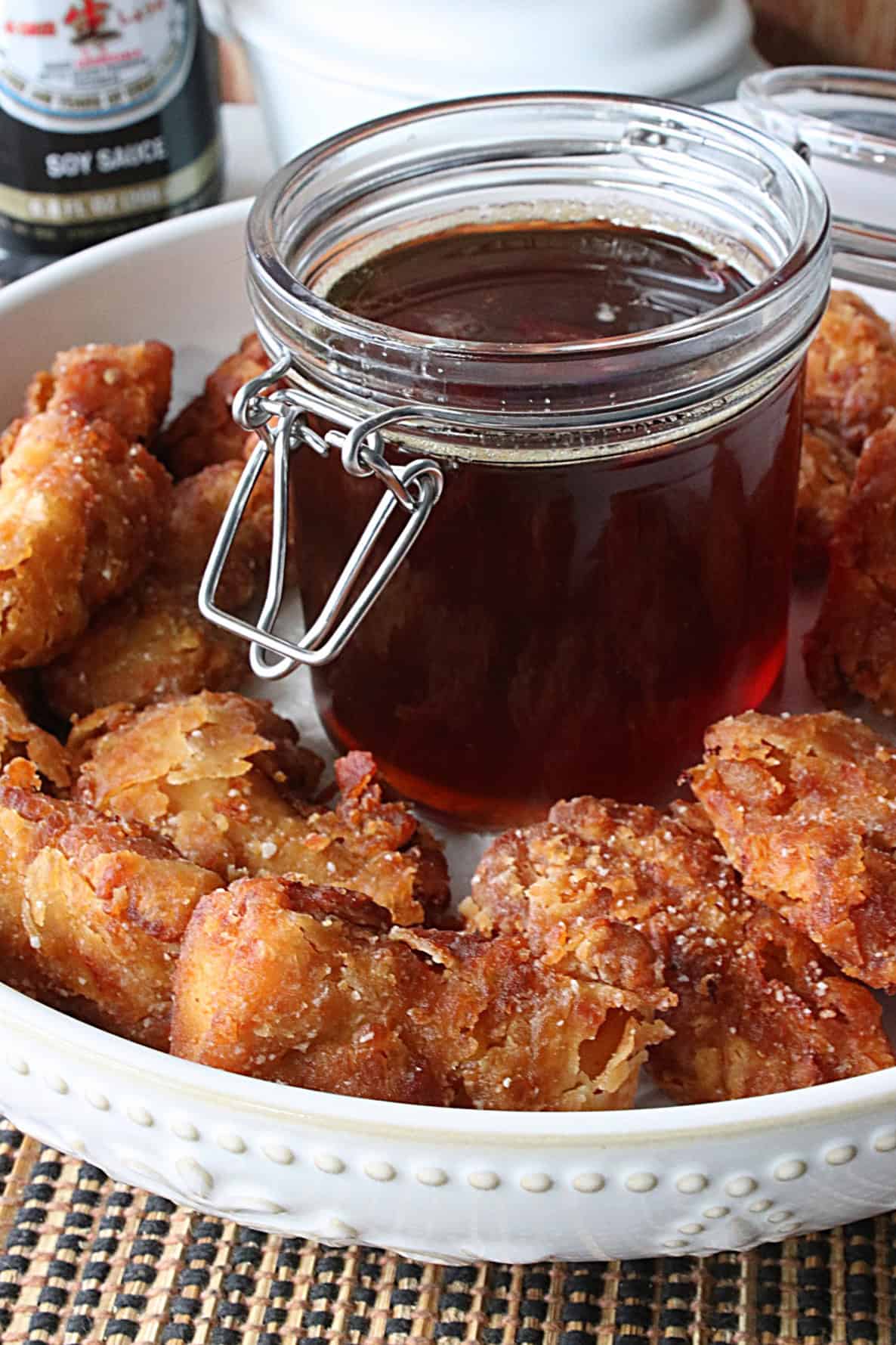 A jar of honey in the middle of a bowl of Japanese Fried Chicken Nuttets.