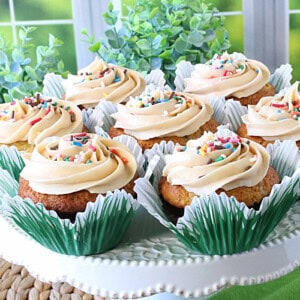 A square image of banana cupcakes on a cake stand.