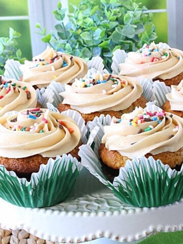 A square image of banana cupcakes on a cake stand.