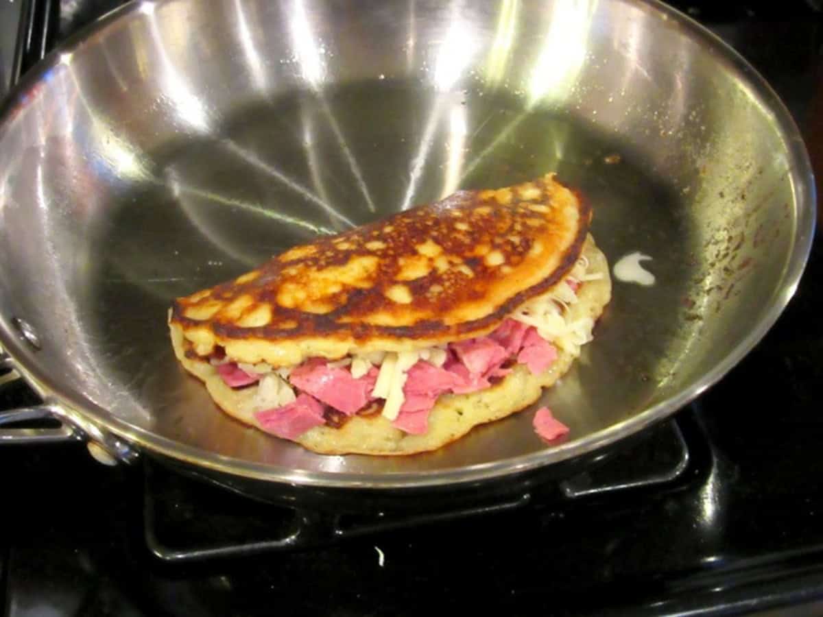 A golden, folded Irish corned beef and Swiss boxty in a skillet.