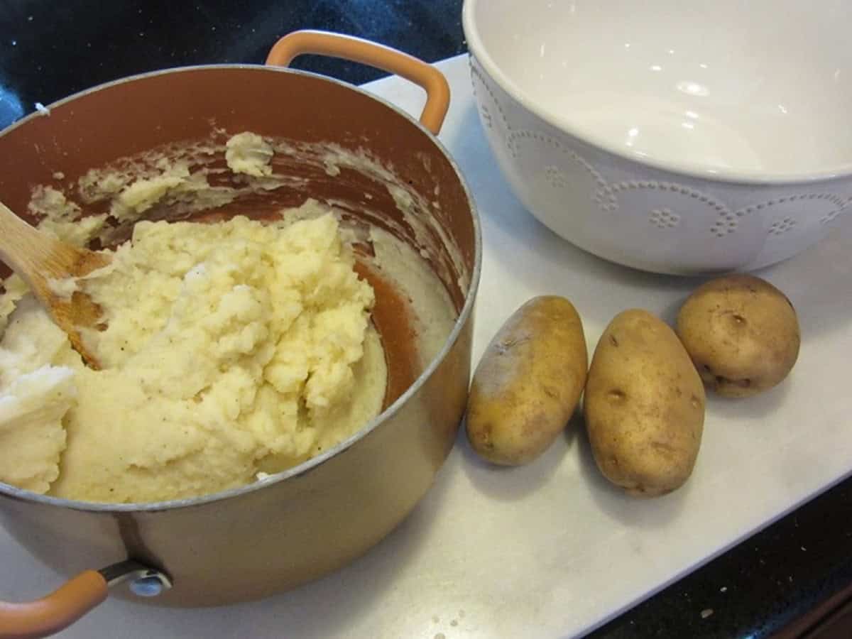 Idaho russet potatoes next to a pot of mashed potatoes.