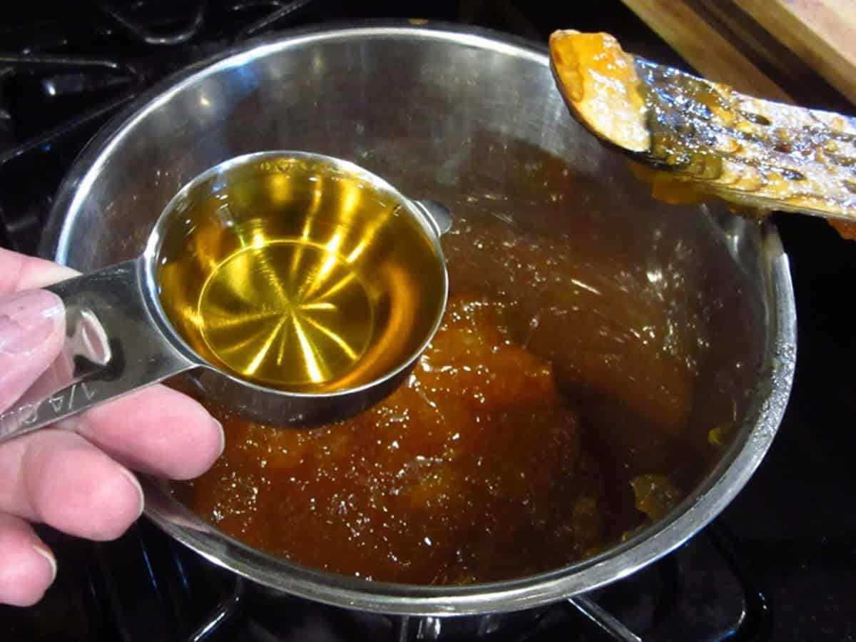 A measuring cup with whiskey being added to a glaze sauce.