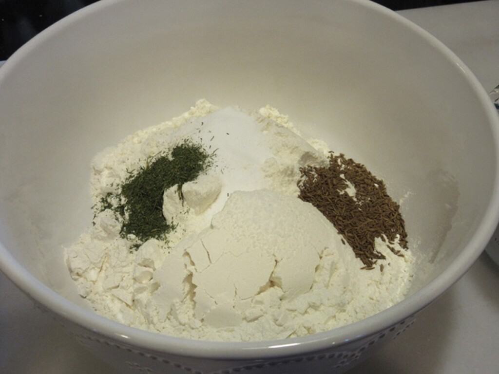 Flour, dill, caraway and salt in a white bowl.
