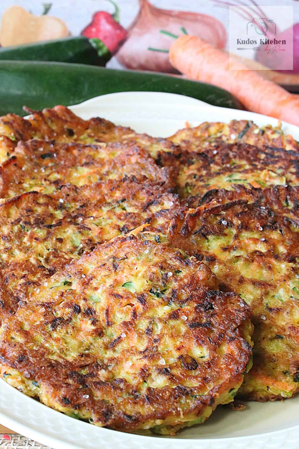 Specks of salt on a platter of zucchini and carrot vegetable pancakes.