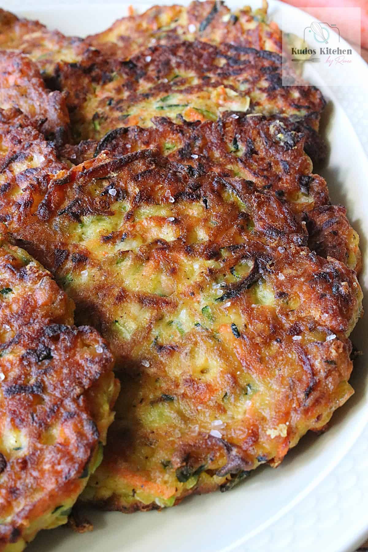 A round, golden zucchini and carrot vegetable fritters on a platter.