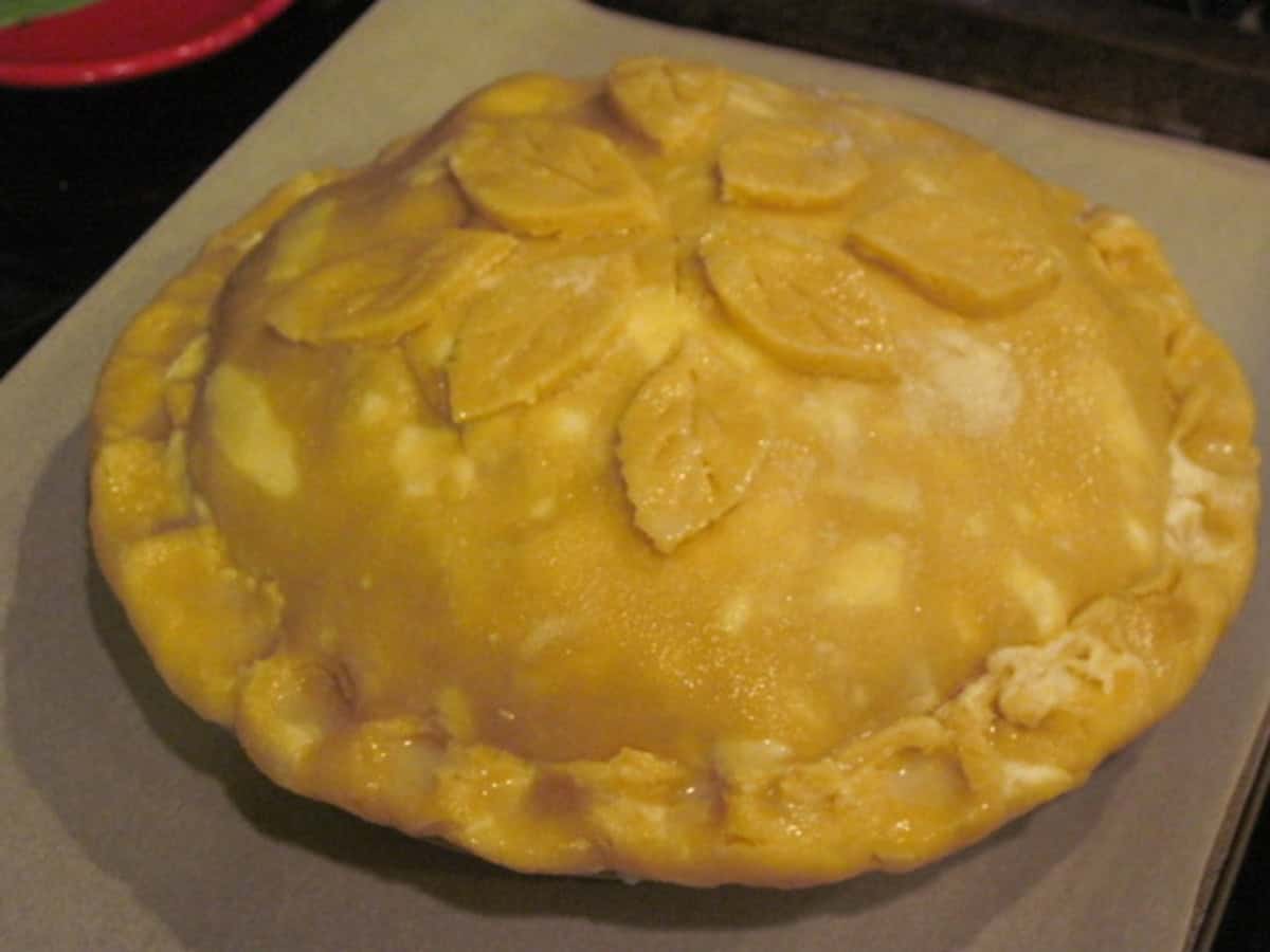 The top crust of an apple pear pie brushed with cream and sugar.
