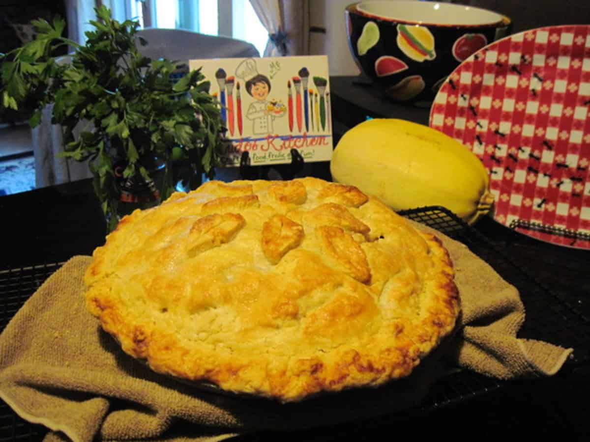 An apple pear pie on a kitchen counter with kitchen accessories in the background.