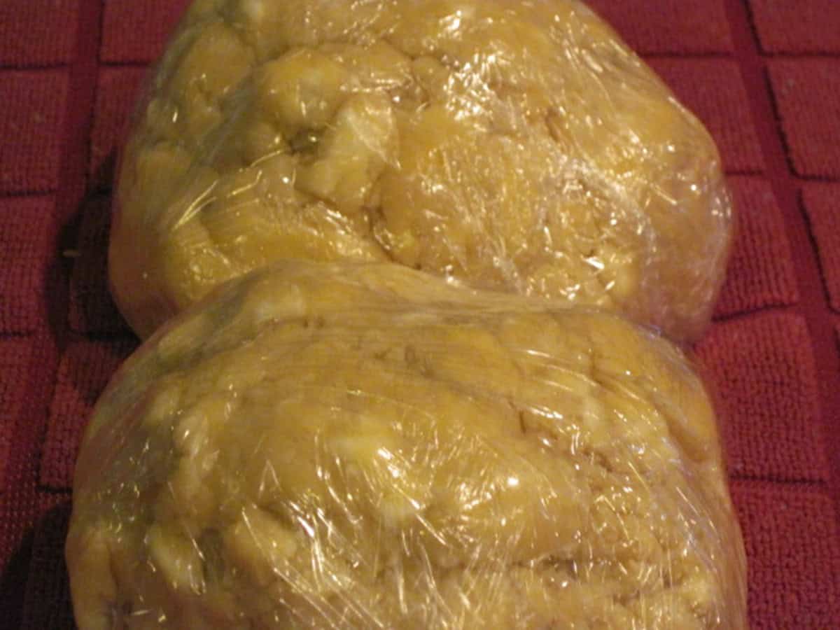 Two balls of pie crust dough wrapped in plastic wrap.