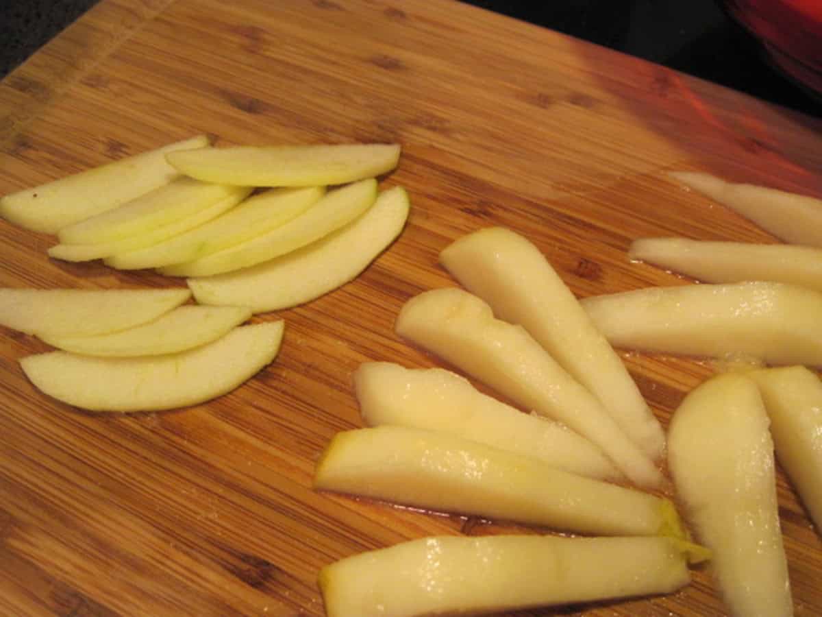Sliced apples and pears on a wooden cutting board.
