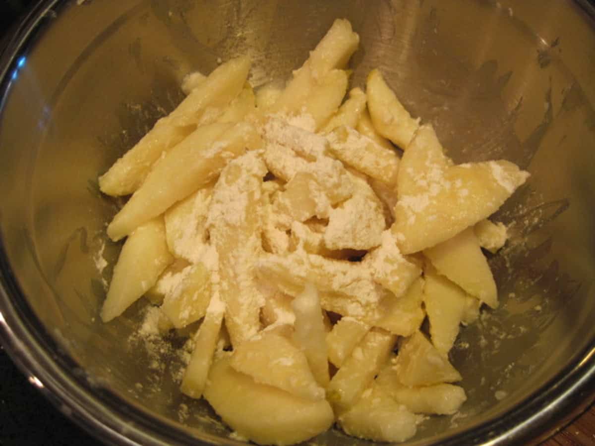 Apple and pear slices along with flour in a bowl for baking a pie.
