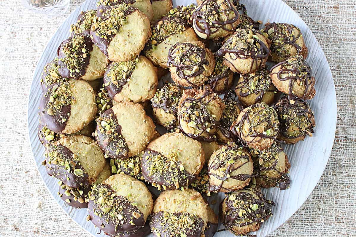 A round platter piled high with Dubai chocolate bar cookies with chocolate and pistachios.