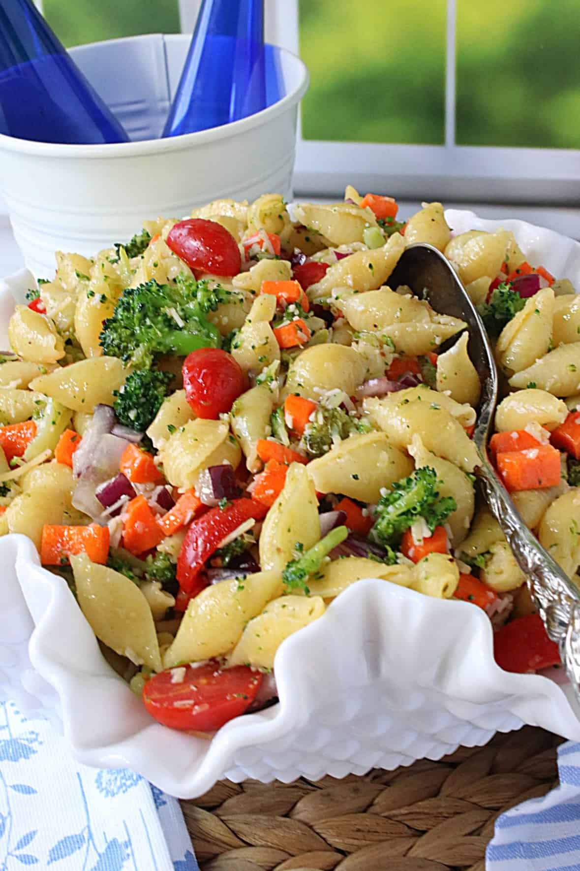 A shell pasta salad with fresh veggies in a pretty white bowl.