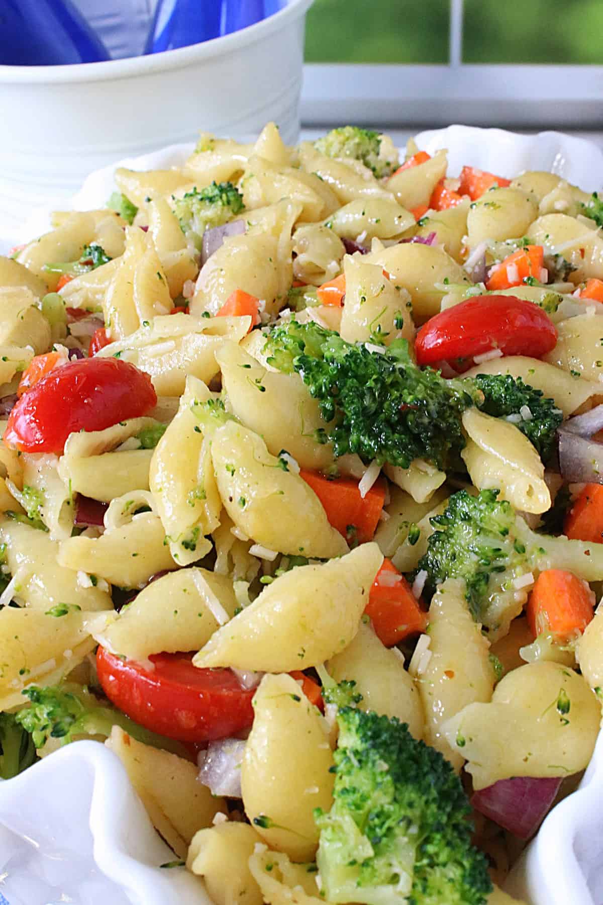 Broccoli, carrots, tomatoes and cheese in a cooked shell pasta salad.
