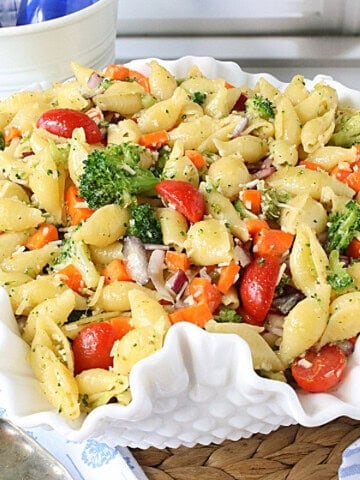 A fluted white bowl filled with Oil and Vinegar Veggie Pasta Salad.