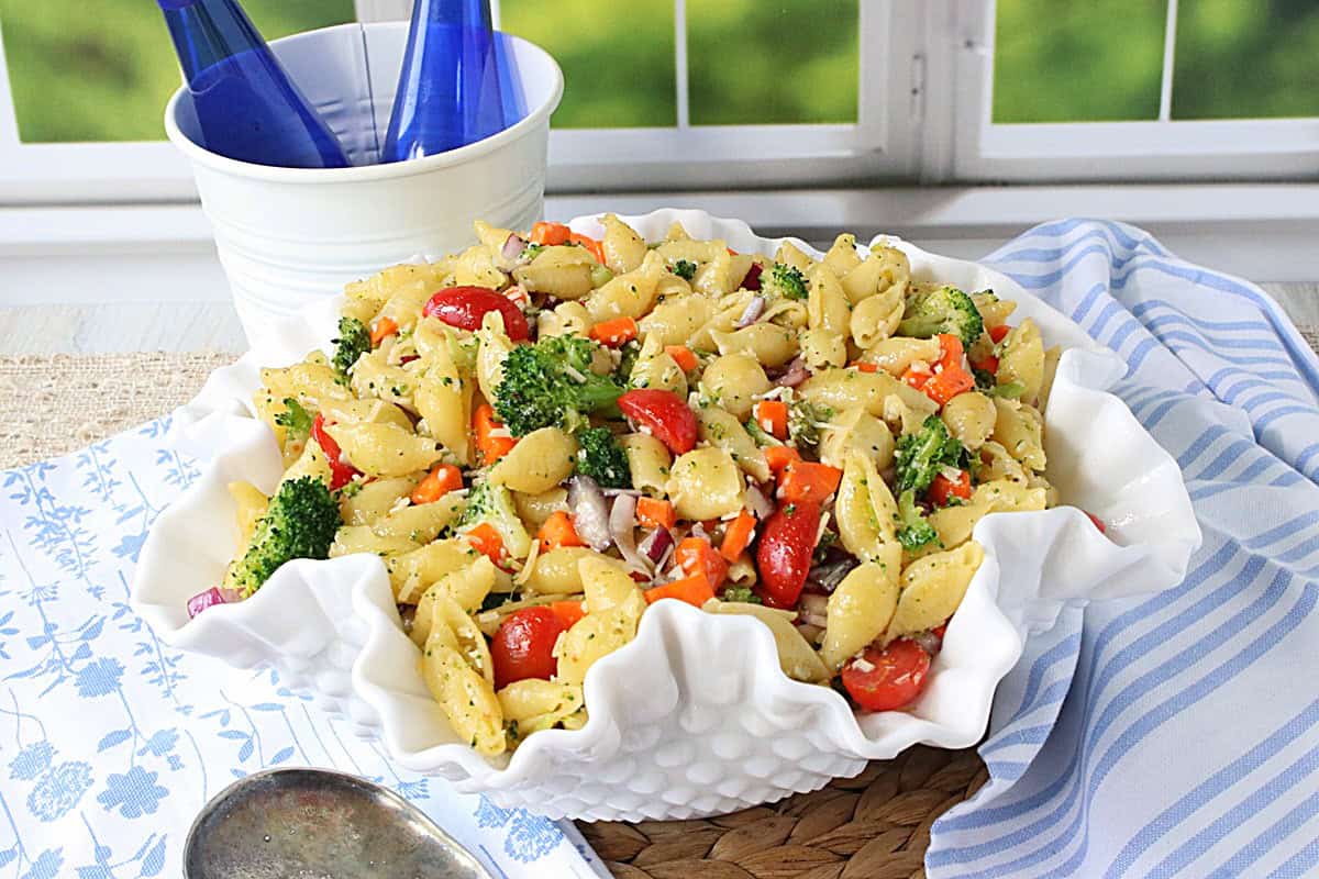 A chilled shell pasta salad in a pretty white fluted bowl.