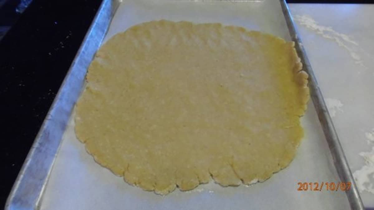 A homemade pie crust rolled out on a baking sheet.