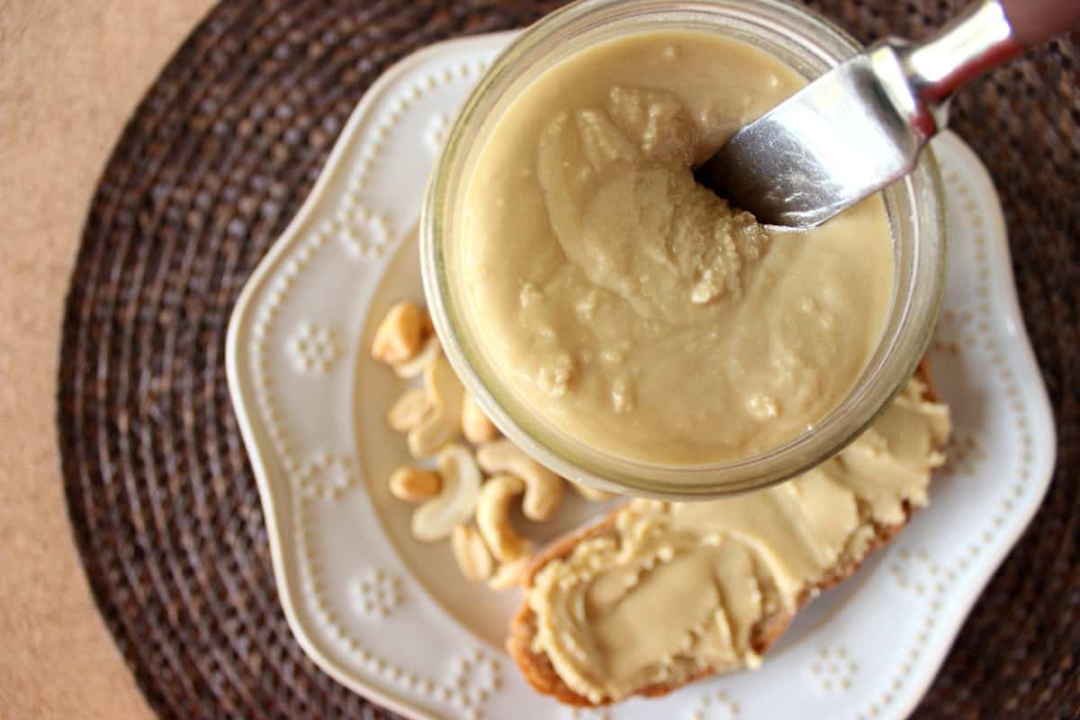 Looking into a jar of roasted cashew butter that also has a knife poking out.