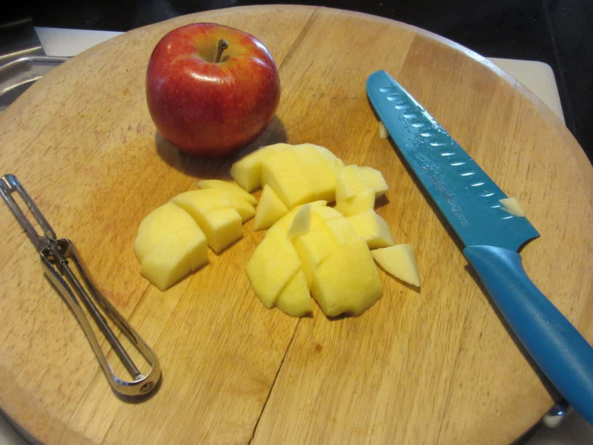 A peeled and chopped apple on a wooden cutting board.