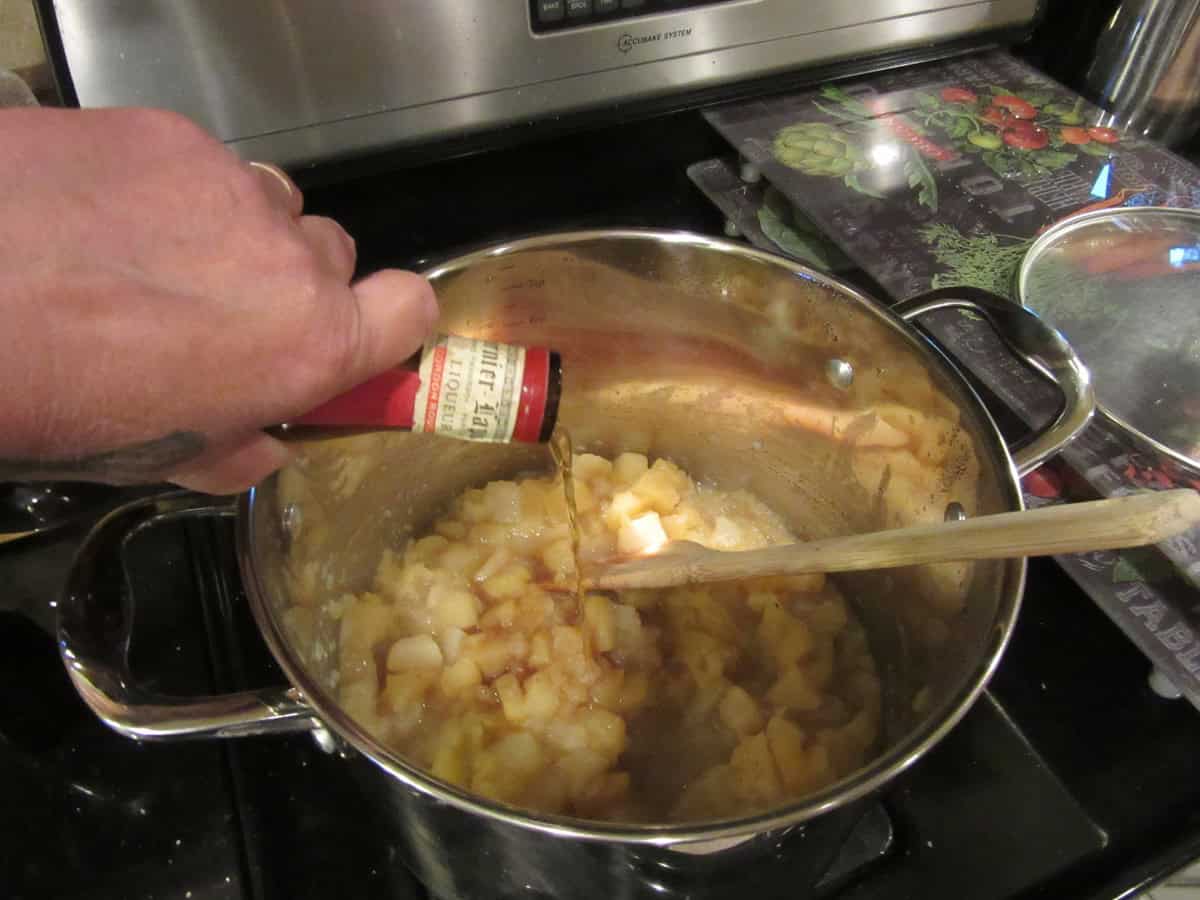 Some Grand Marnier being poured into a pot of apple and pear sauce.