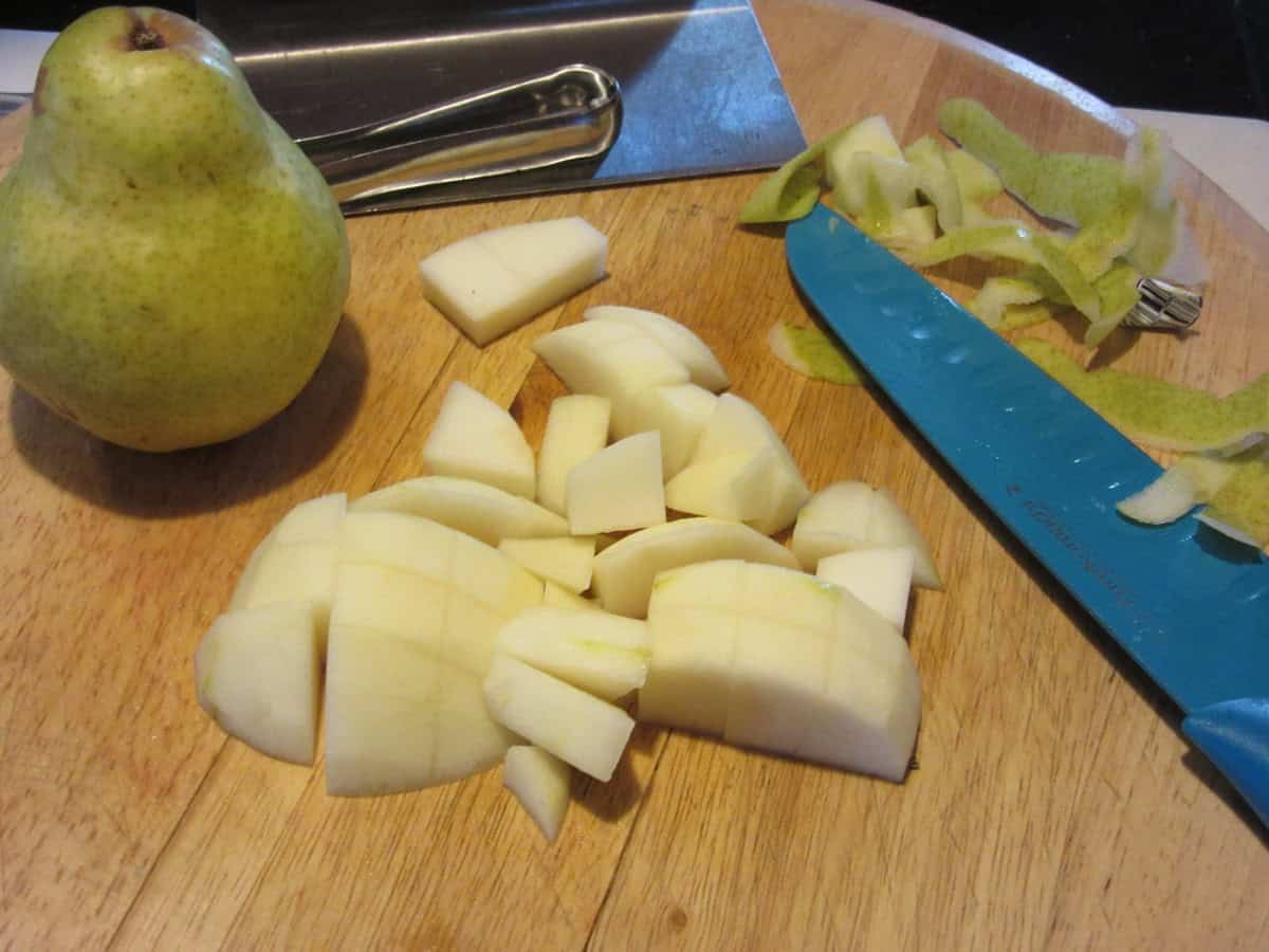 A peeled and chopped pear on a cutting board.