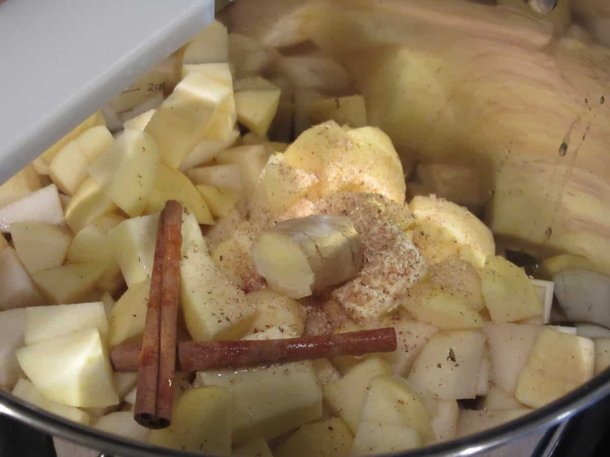A knob of fresh ginger in a pot of chopped apples and pears.