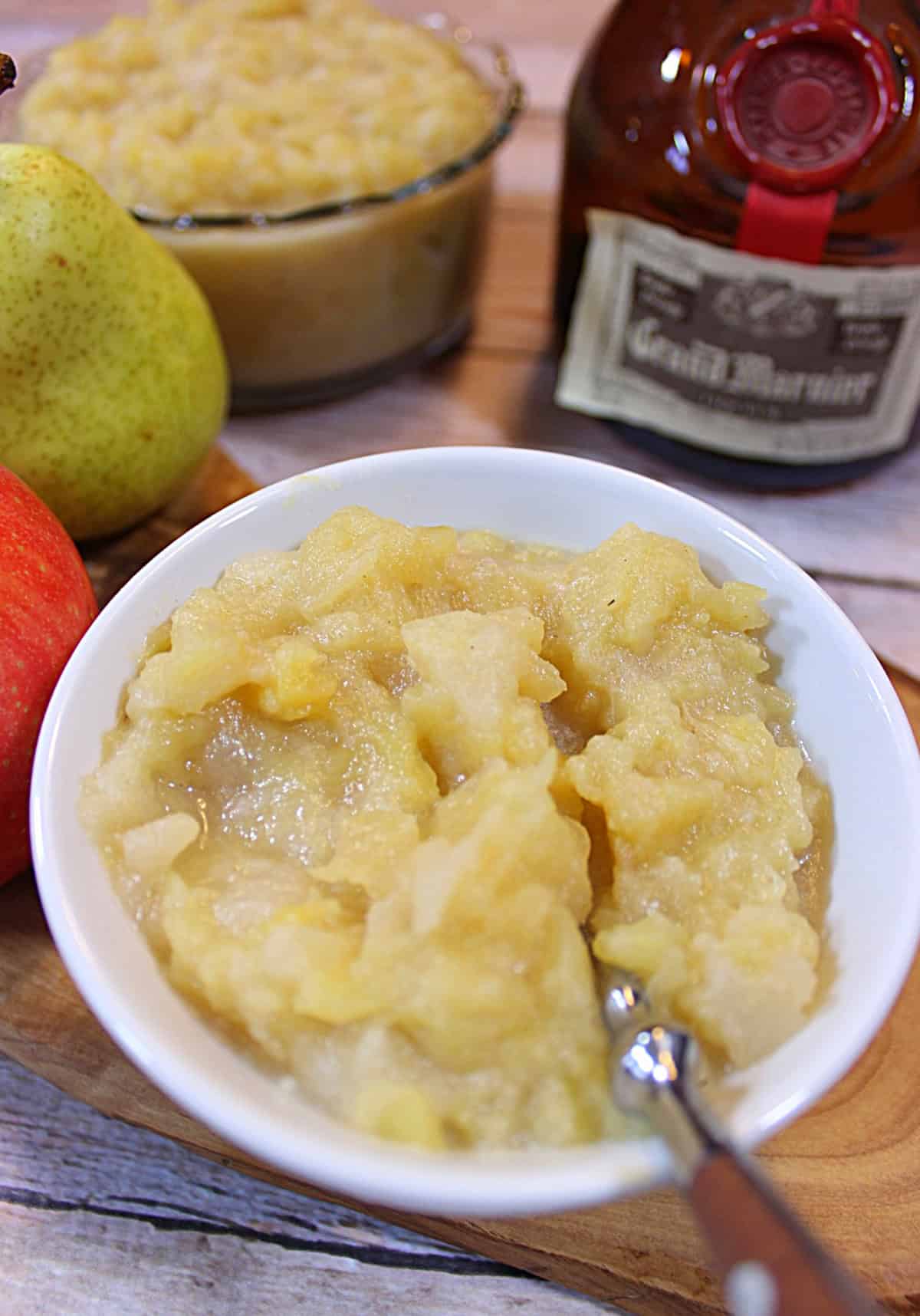 Apple Pear Sauce with Grand Marnier - www.kudoskitchenbyrenee.com A white bowl with a spoon filled with apple and pear sauce.