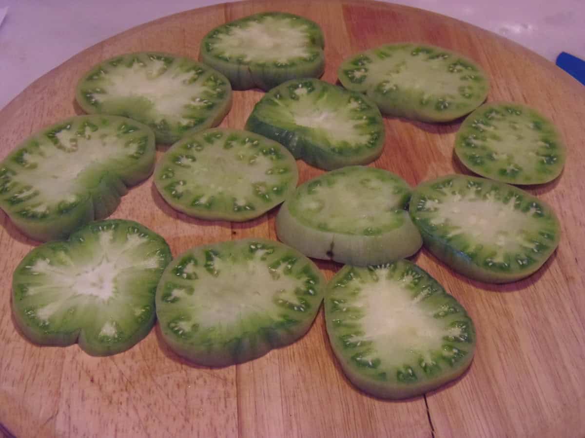 Sliced green tomatoes on a wooden cutting board