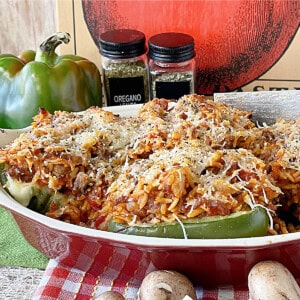 Four Italian Stuffed Bell Peppers in a red casserole dish topped with cheese.