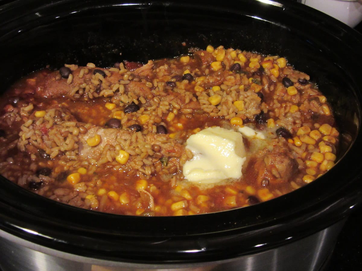 Rice, beans and corn in a slow cooker with a pat of butter.