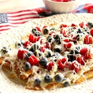 A white platter filled with cinnamon sugar dessert nachos topped with berries.