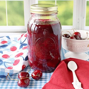Cherry Pie filling in a jar by a window.