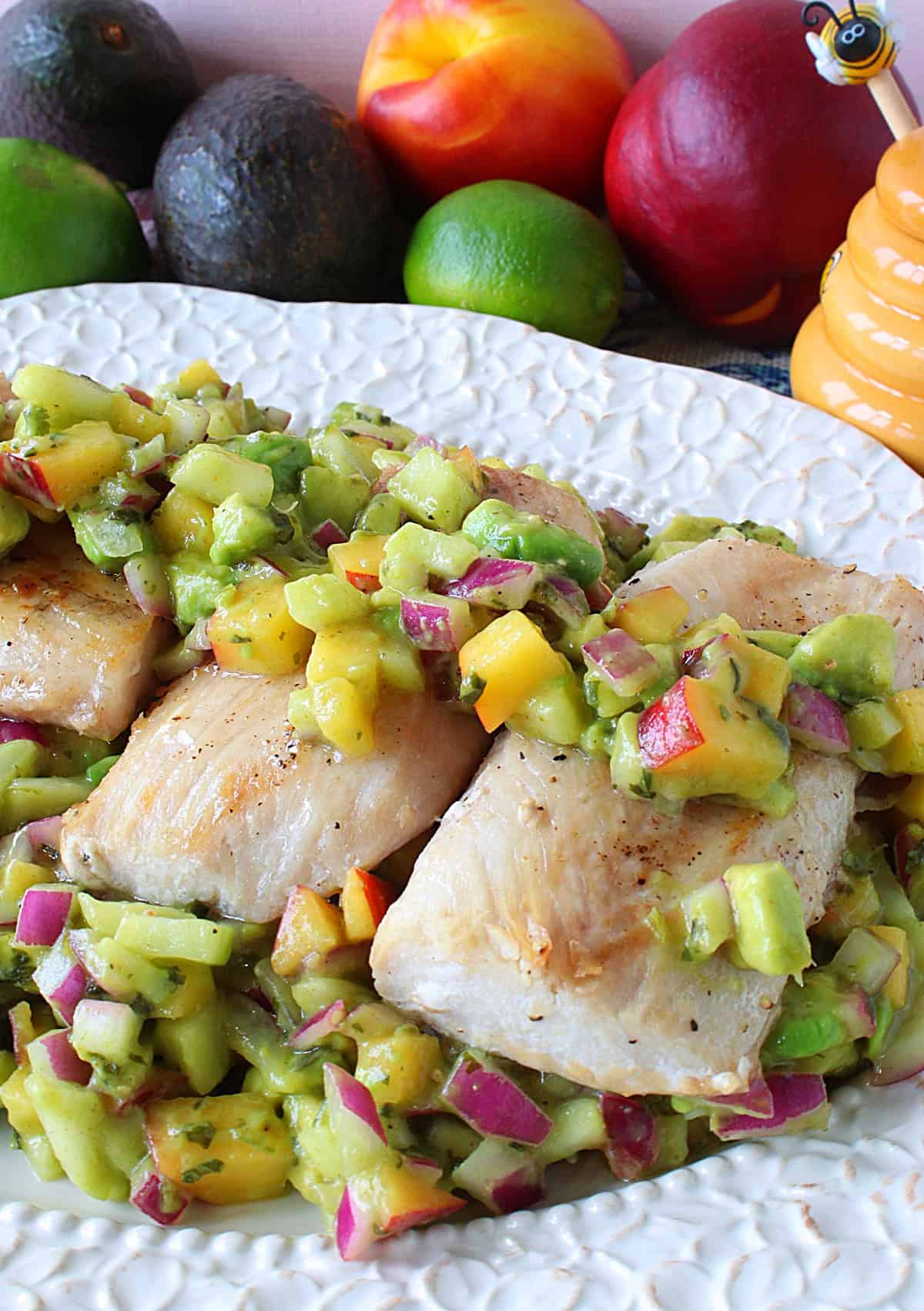 Healthy Seared Mahi Mahi with Nectarine Avocado Salsa is the perfect summertime meal that will help you beat the heat, and keep you feeling light on your toes. - www.kudoskitchenbyrenee.com A colorful platter of fish filets with fruit salsa and fresh fruit in the background.