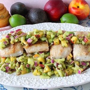 Four seared mahi mahi filets on a platter with colorful fruit and vegetable salsa.