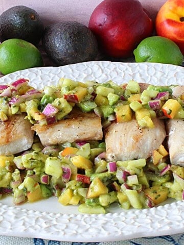 Four seared mahi mahi filets on a platter with colorful fruit and vegetable salsa.