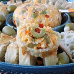 A baguette slice piled high with pimento cheese with olives.