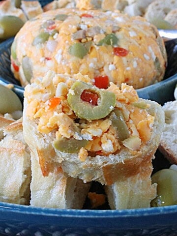 A baguette slice piled high with pimento cheese with olives.