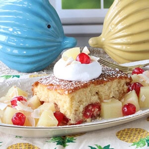 A dollop of whipped cream and a cherry on top of a slice of Piña Colada Dump Cake.