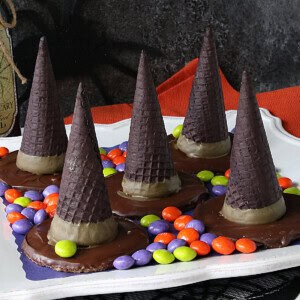 Five candy filled with hat Halloween treats on a platter surrounded by skittles.
