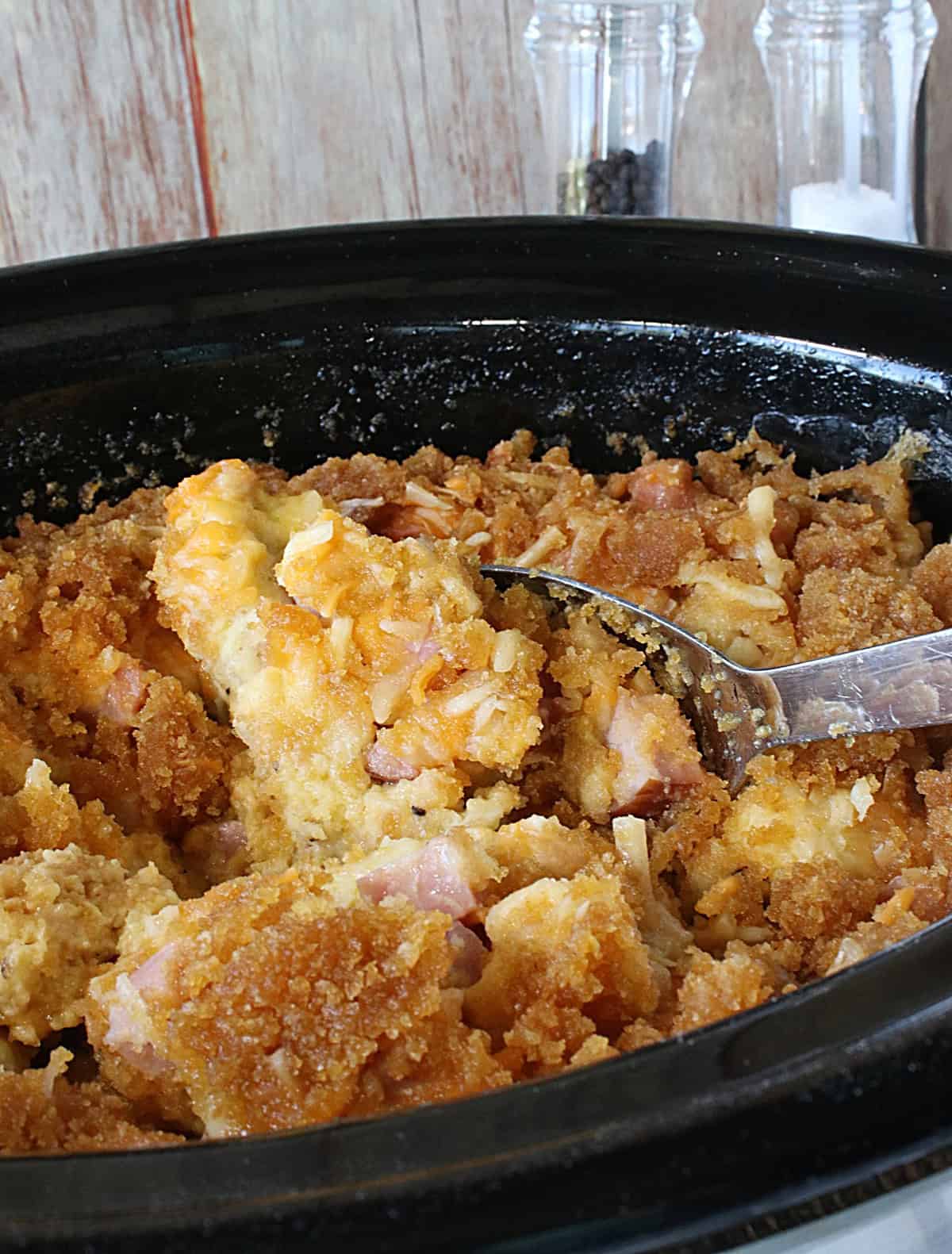 Slow cooker ham and cheese strata inside of a black crock of the slow cooker.