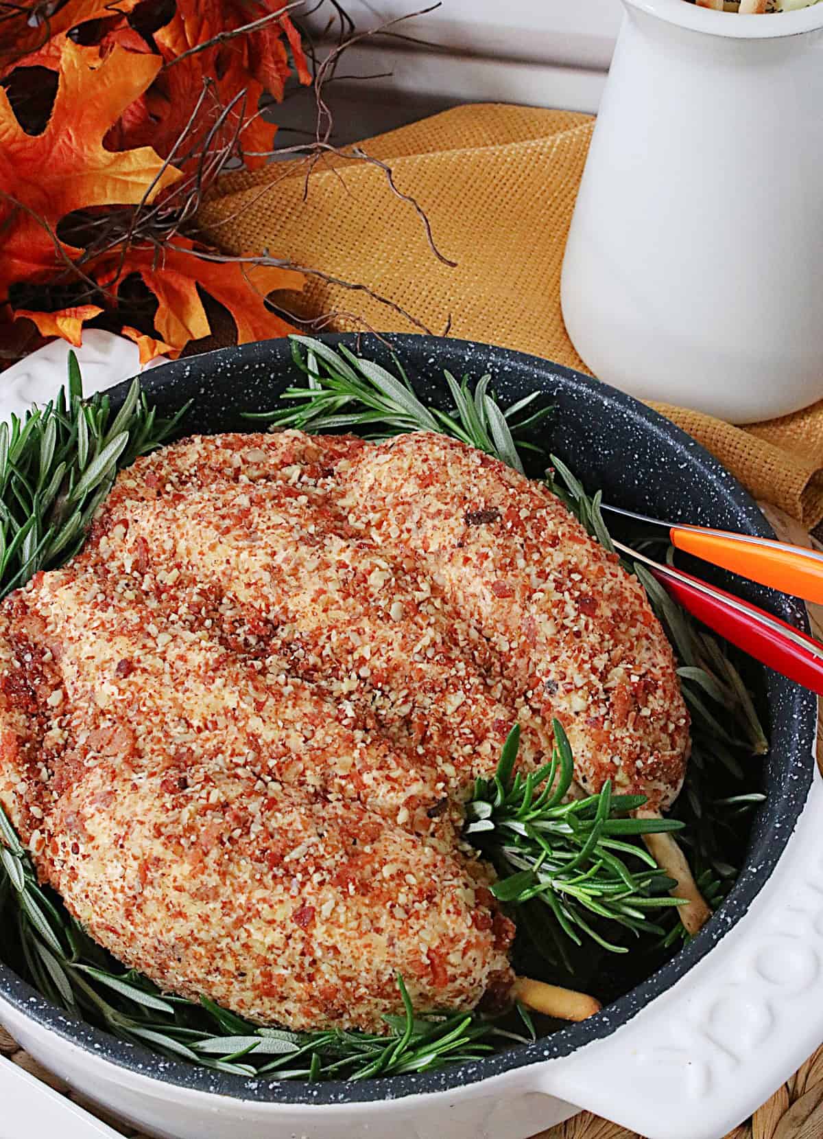 A realistic looking pecan topped turkey cheeseball in a roasting pan.