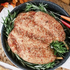 A fun and realistic looking turkey cheeseball for Thanksgiving with fresh rosemary in a roasting pan.