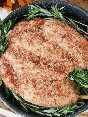 A fun and realistic looking turkey cheeseball for Thanksgiving with fresh rosemary in a roasting pan.