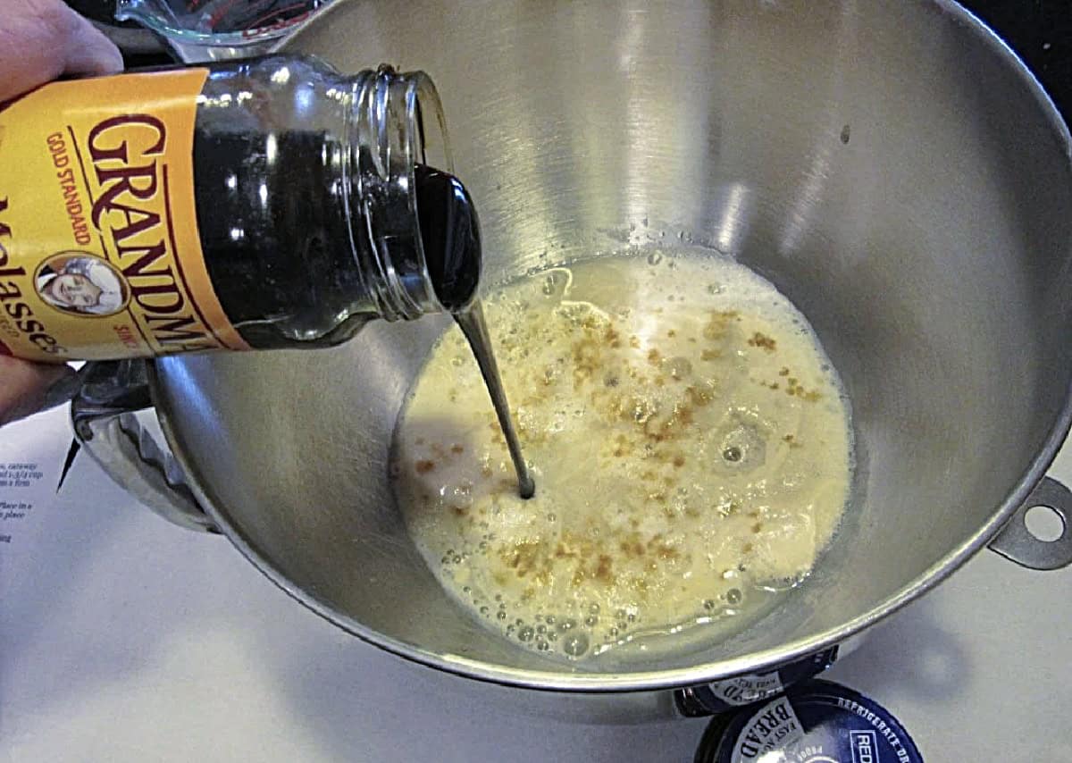 Molasses being poured into a bowl with wet ingredients.