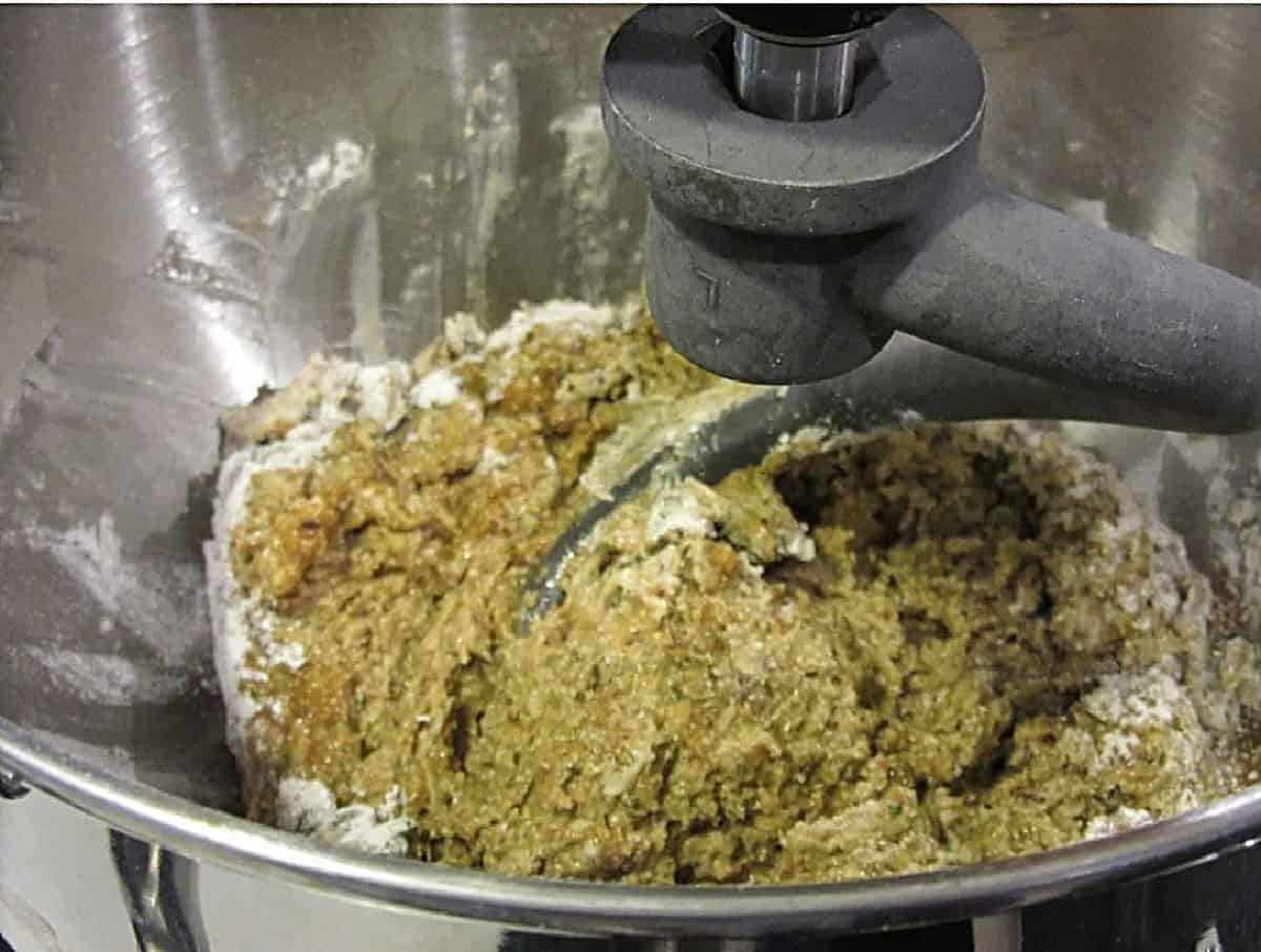 A wet rye dough in a stand mixer with a dough hook.