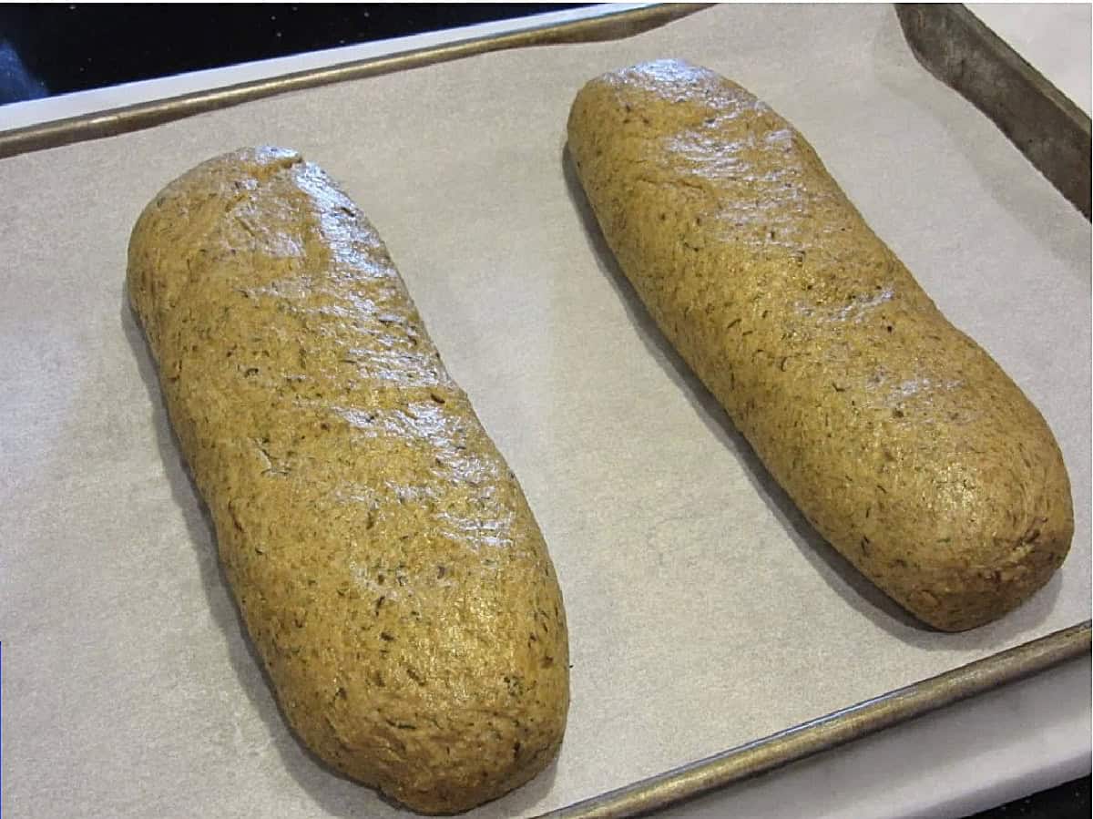 Two long unbaked loaves of rye bread before baking.