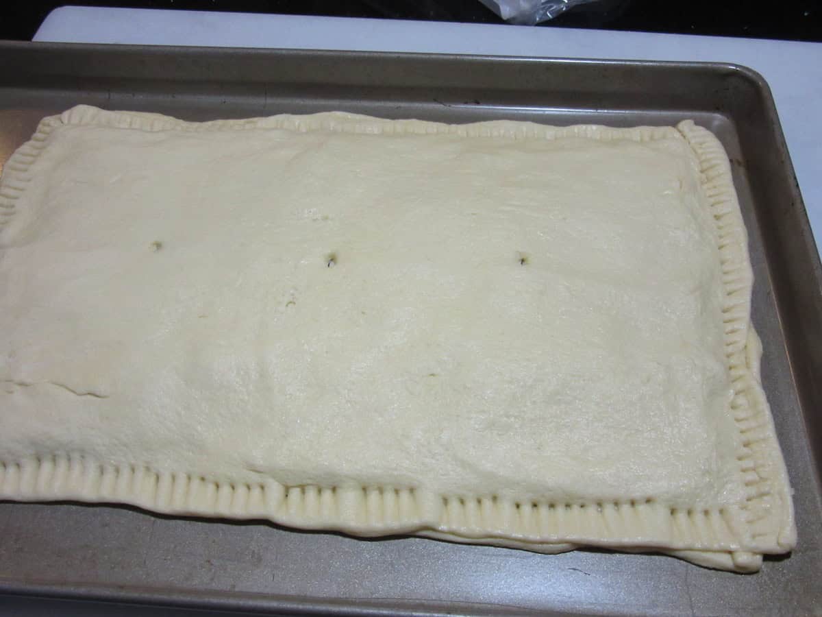 Two sheets of crescent roll dough on a baking sheet for an appetizer.