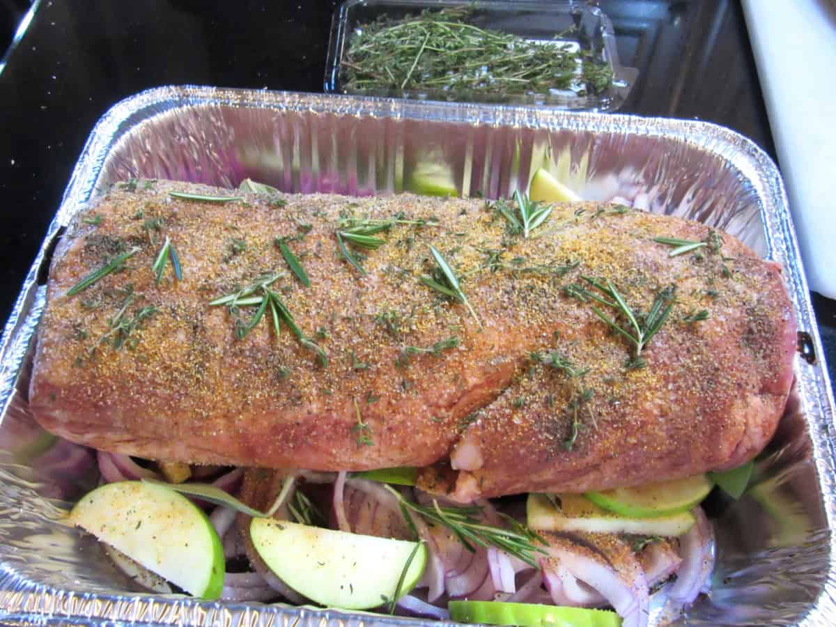 A Pork uncooked seasoned pork roast in a roasting pan.