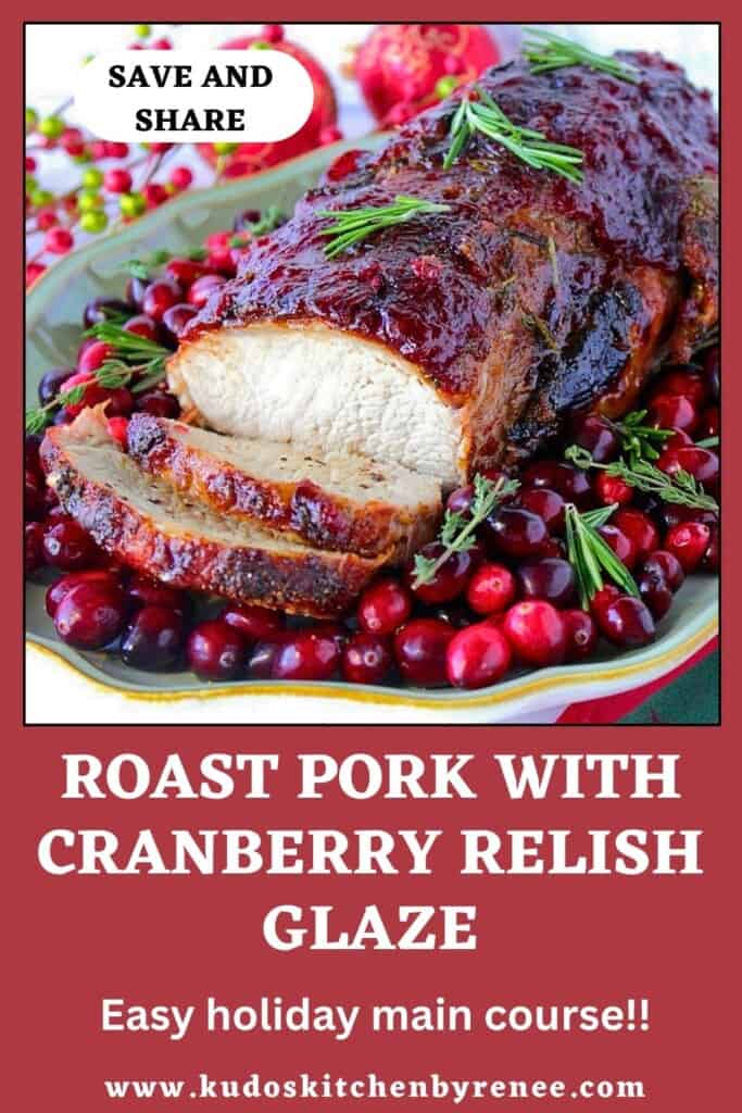 A cranberry glazed pork roast surrounded by fresh cranberries and rosemary sprigs.