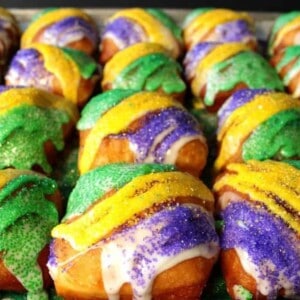Brightly colored Mardi Gras Beignets iced and with colored purple, green, and gold sanding sugar.