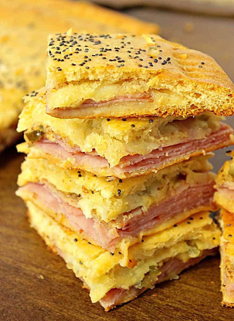A stack of ham and cheese crescent appetizer squares with melted cheese in the middle.